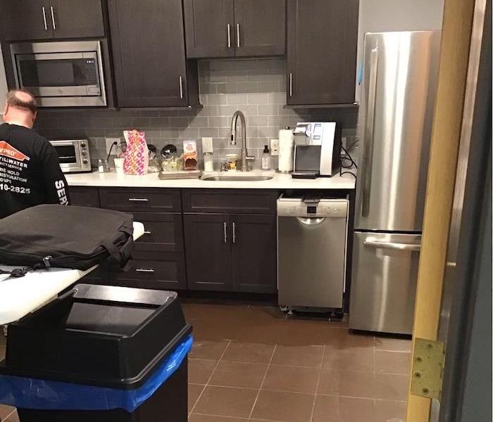 kitchen with SERVPRO technician standing in front of cabinets and appliances 