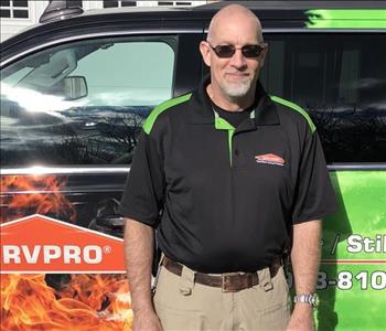 Male SERVPRO employee standing in front of a SERVPRO vehicle. 