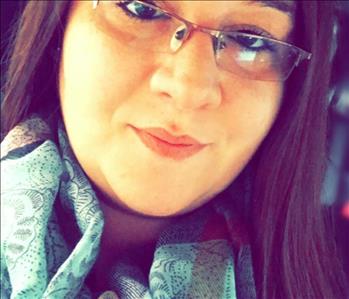 A woman with glasses on and a green scarf.