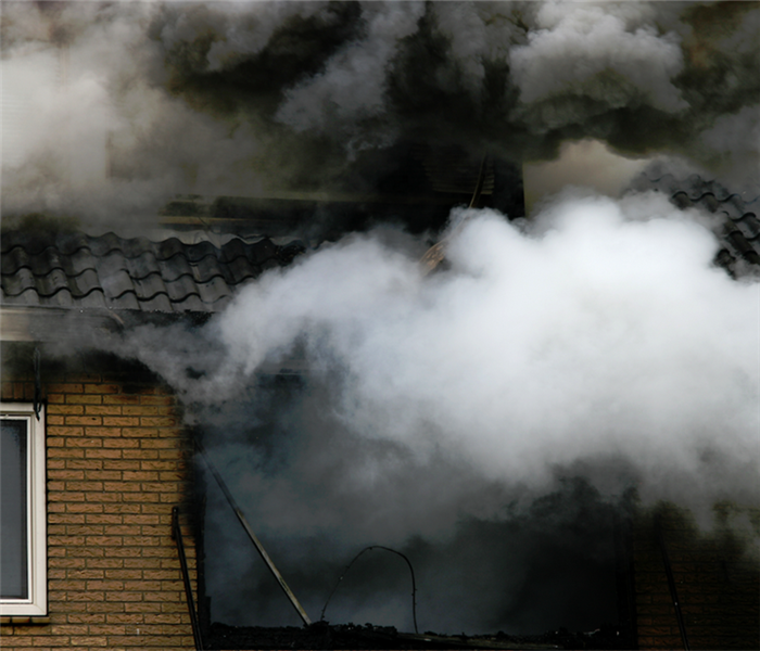 smoke billowing out of the windows of a house