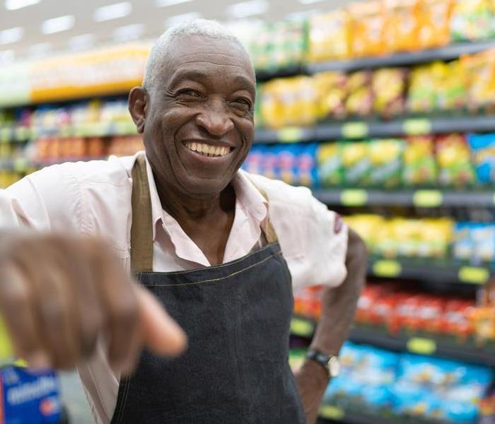 A stock man at a grocery store smiling. 