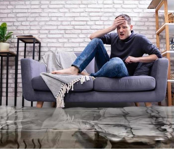 Water in living room; Man on couch